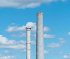 pijpen van een industriële onderneming tegen een blauwe lucht met wolken. schoorsteen zonder rook foto