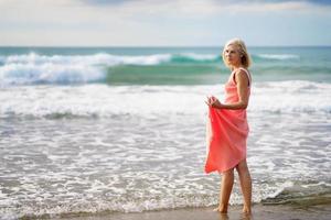 volwassen vrouw geniet van haar vrije tijd kijkend naar de zee vanaf de kust van het strand.