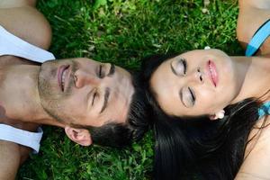 gelukkig lachend paar dat op groen gras ligt foto