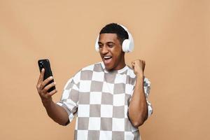vreugdevolle afrikaanse man die met een koptelefoon naar de telefoon kijkt foto