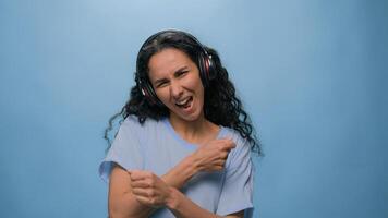 studio portret gelukkig glimlachen het zingen Arabisch vrouw Indisch dame spaans meisje luisteren naar muziek- met hoofdtelefoons dansen luister radio dans Actie Bij blauw achtergrond koptelefoon geluid audio pret lied ritme foto