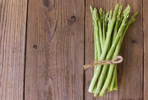 Asperges op houten ondergrond - verse groene asperges foto