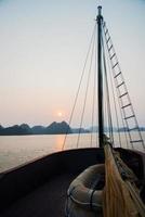 uitzicht op Halong Bay vanaf een zeilboot tijdens zonsondergang. veiligheidsboot op de grond. Vietnam foto