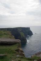 kliffen van moher op een regenachtige dag. groene velden en kalm water. Ierland foto