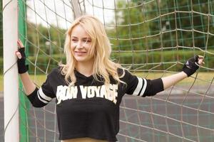 mooie blonde binnen het voetbalraster houdt vast en glimlacht. foto