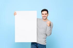 knappe blanke man die leeg Witboekbord toont met vuist die op lichtblauwe geïsoleerde achtergrond opheft foto