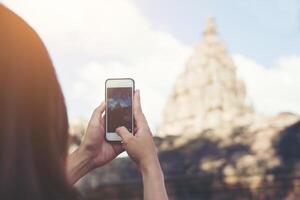 jonge aantrekkelijke vrouw fotograaf toerist met rugzak komt om foto te schieten met haar smarphone bij oude phanom rung tempel in thailand.