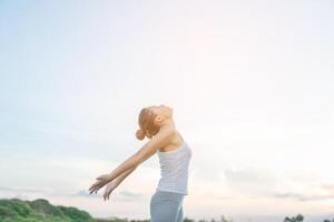 jonge mooie vrouw die handen opsteekt met een prachtig uitzicht op de weide geniet van frisse lucht. foto