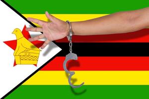 handboeien met hand op de vlag van Zimbabwe foto
