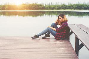 triest hipster vrouw zittend op de pier met verdriet. foto