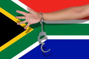 handboeien met hand op de vlag van Zuid-Afrika foto