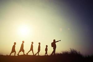 silhouetten kinderen en ouder wandelen met rugzakken. tijd om samen te gaan reizen. foto