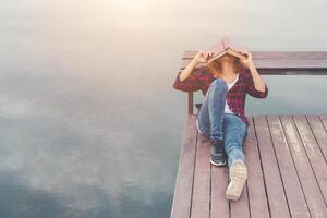 jonge, mooie hipster-vrouw die moe was na het lezen, legde het boek op haar hoofd om een dutje te doen op de toren. foto