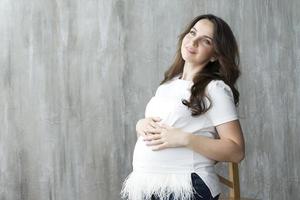 zwanger meisje op grijze achtergrond.