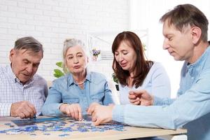 senior paar oplossen puzzel samen met familie thuis. foto