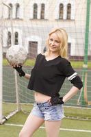 mooie blonde met een bal bij het voetbaldoel. foto