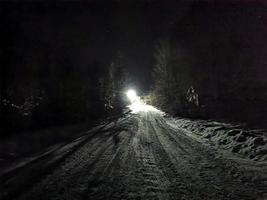 besneeuwde weg op een maanverlichte winternacht in het dorp foto
