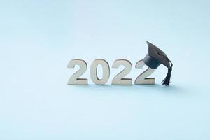 afstuderen 2022 met afgestudeerde hoed op houten nummer 2022 op blauwe achtergrond, klasse van 2022 foto