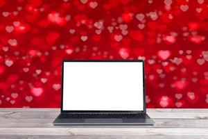 mock-up laptop op een houten tafel op rode hartvormige bokeh achtergrond foto