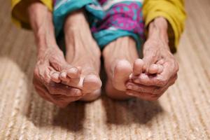 close-up op senior vrouwen voeten en handmassage op blessure plek. foto