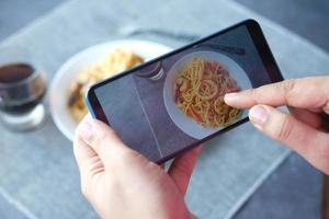 een foto maken van een bord pasta met zeevruchten met smartphone