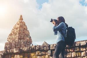 jonge aantrekkelijke vrouw fotograaf toerist met rugzak komt om foto te schieten op de oude phanom rung tempel in thailand.