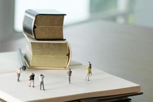 creatief ideeconcept - miniatuurfotograaf met uitstekend gouden boek op open document notitieboekje foto