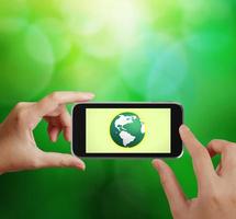 hand met de telefoon tablet touch computer gadget met groene wereldbol als concept foto