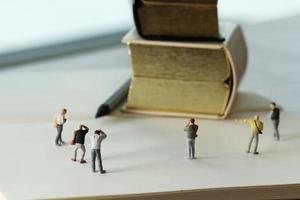 creatief ideeconcept - miniatuurfotograaf met uitstekend gouden boek op open document notitieboekje foto