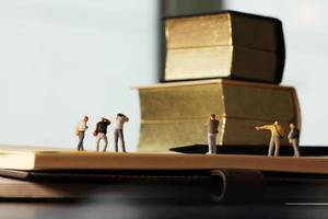 creatief ideeconcept - miniatuurfotograaf met uitstekend gouden boek op open document notitieboekje foto