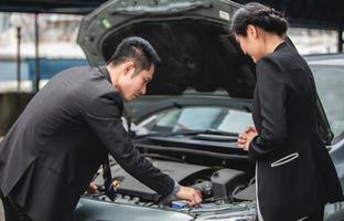 zakenlieden helpen zakenvrouwen bij het controleren en repareren van kapotte auto's foto