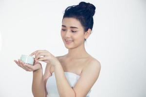 een mooie aziatische vrouw die een huidverzorgingsproduct, vochtinbrengende crème of lotion gebruikt die voor haar droge teint zorgt. hydraterende crème in vrouwelijke handen. foto