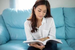 Aziatische vrouwen glimlachen en lezen een boek om thuis te ontspannen foto