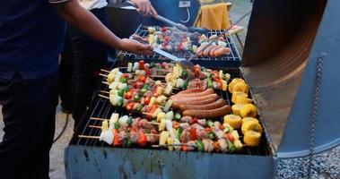 Aziatische groep vrienden met barbecue in de buitenlucht die 's nachts lacht met alcoholische bierdranken foto