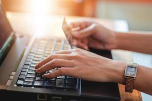 Aziatische vrouw die laptop en creditcard gebruikt om online te winkelen, selectieve focus op de hand, zachte focus en vintage toon foto