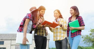 groep studenten lachen en plezier hebben het helpt ook om ideeën in het werk en project te delen. en bekijk ook het boek voor het examen buiten in de tuin. foto