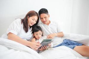 familie en zoon kijken en spelen tablet op bed foto