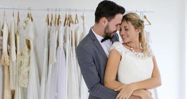 de geliefden geven bloemen aan de bruid en kusten gelukkig en het paar houdt van staande in de trouwstudio foto