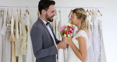 de geliefden geven bloemen aan de bruid en kusten gelukkig en het paar houdt van staande in de trouwstudio foto