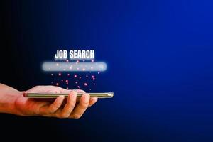 baan zoeken concept. hand met smartphone met een zoekvak voor het zoeken naar een baan op een blauwe achtergrond met kopieerruimte. foto