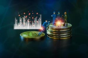 miniatuur mensen teamwork, klein model menselijke figuur staande op gouden munten stapel met blauwe en witte grafiek. cryptocurrency of digitaal geldconcept. foto