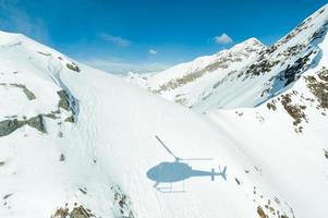 helikopterschaduw geprojecteerd op sneeuw op bergen foto