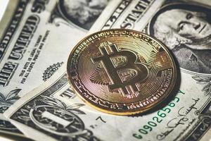een bitcoin-munt die op ons papieren dollars rust foto