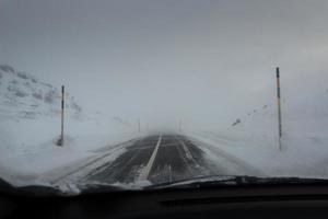 rijdende auto bergweg met sneeuwstorm foto