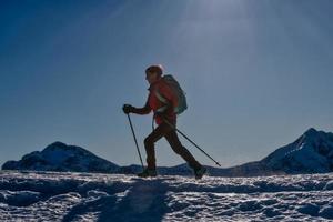 sportieve vrouw loopt op sneeuw met stijgijzers en stokken foto