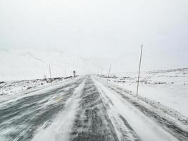 rijden door blizzard sneeuwstorm met ijzel op de weg, noorwegen. foto