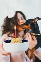 gelukkig jong meisje dat zelfgemaakte cake geeft aan haar hond, binnenshuis foto