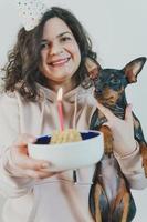 gelukkig jong meisje dat zelfgemaakte cake geeft aan haar hond, binnenshuis foto