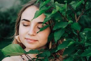 portret van een mooi blond meisje met gesloten ogen in een groene bladeren bomen. kopiëren, lege ruimte voor tekst. kopiëren, lege ruimte voor tekst