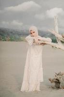 mooi islamitisch vrouwelijk model met hijab-mode, een moderne trouwjurk voor moslimvrouwen loopt langs het zand en de zee. een Aziatisch meisjesmodel dat hijab gebruikt en plezier heeft op het strand. foto prewedding